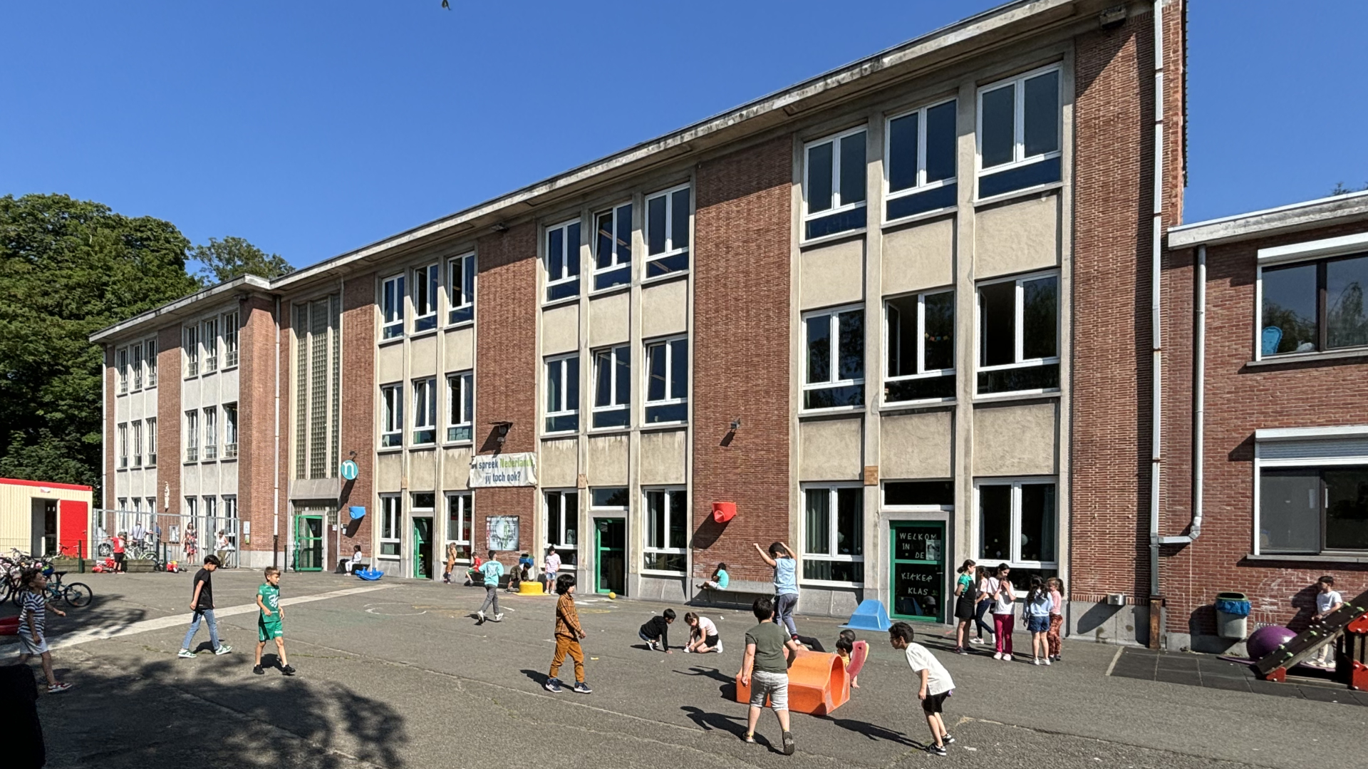 Foto van de speelplaats met spelende kinderen en het gebouw van de Vrije Basisschool Sint-Martinus in Molenbeek - Foto (c) Bruno De Lille